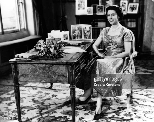 Queen Elizabeth II smiling towards The Prince Philip, Duke of Edinburgh just before the end of her first Christmas Day television speech to her...