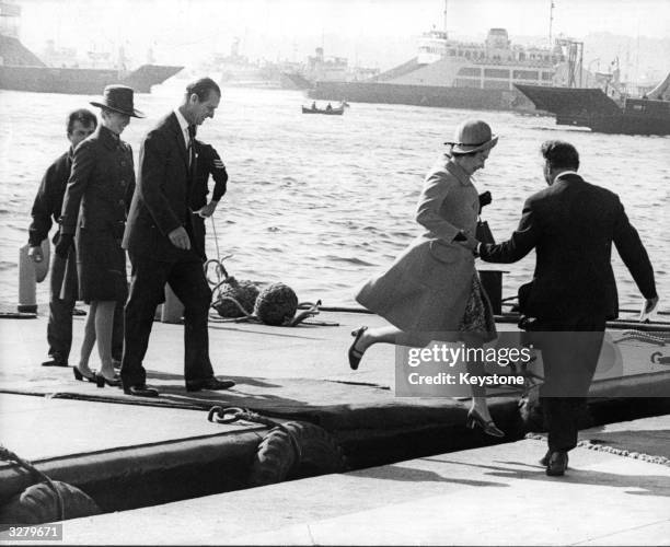 Queen Elizabeth II is given a helping hand as she hops ashore from a floating platform on a visit to Turkey. Prince Philip and Princess Anne are with...