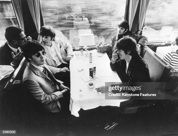 The Beatles relax in the buffet car of a train, during a tour of Europe.