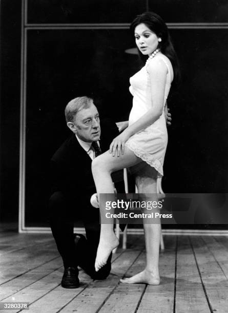 Sir Alec Guinness examines a patient, played by Madeleine Smith, in the stage play 'Habeas Corpus' by Alan Bennett.