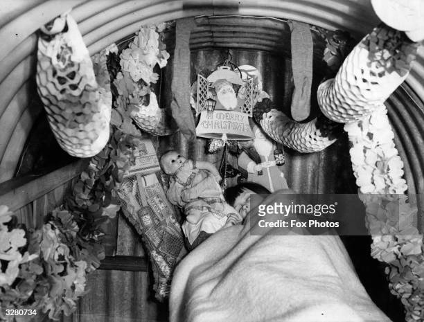 Wartime Anderson shelter festively decorated for a sleeping child's Christmas, Ilford, Essex, 14th December 1940.