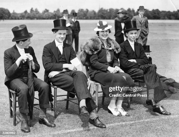 Pupils at Eton sit at the sidelines and watch a cricket match.