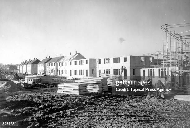 Workmen make progress on a Croydon housing estate, where 14 semi-detached houses are almost complete, with a further 8 under construction. The...