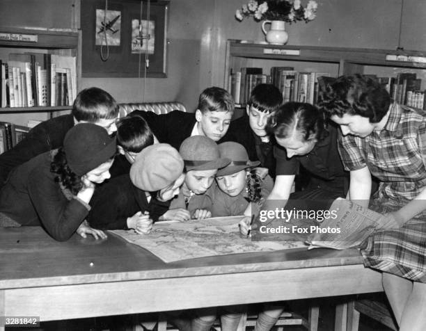 Librarian with the Roath Library at Cardiff explains the latest war moves to some children with the aid of a map.