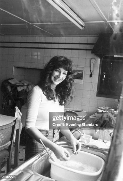 English singer-songwriter and musician Kate Bush doing the washing up at her family's home in East Wickham, London, 26th September 1978.