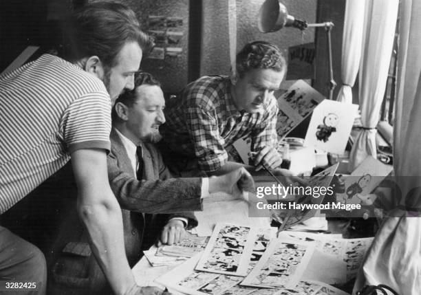 From left to right, scriptwriter Robert Raymond and cartoonist Trog, review the daily cartoon strips of Flook and Rufus with W St J Glen, the 'Daily...