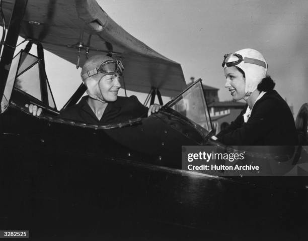 June Travis, the Warner Brothers starlet, taking flying lessons for her film 'Ceiling Zero', from Amelia Earhart , the American airwoman from Kansas...