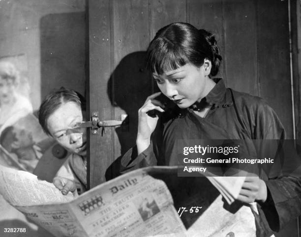 Chinese-American actress Anna May Wong , the stage name of Wong Liu Tsong, reads an article in the newspaper in a scene from 'Piccadilly', directed...