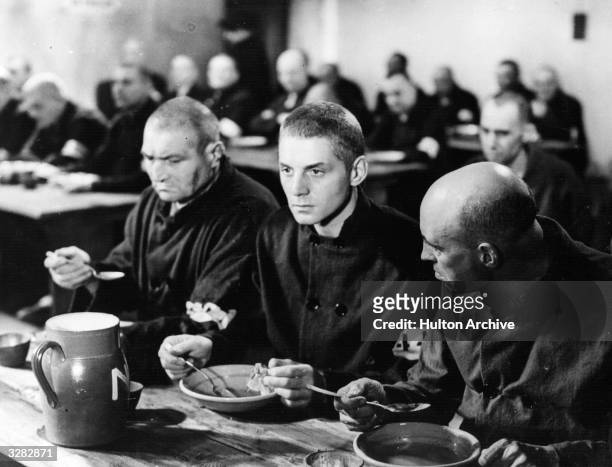 French actor Pierre Fresnay takes a meal with his fellow prisoners in a scene from 'Cheri-Bibi', directed by Leon Mathot for DPF.