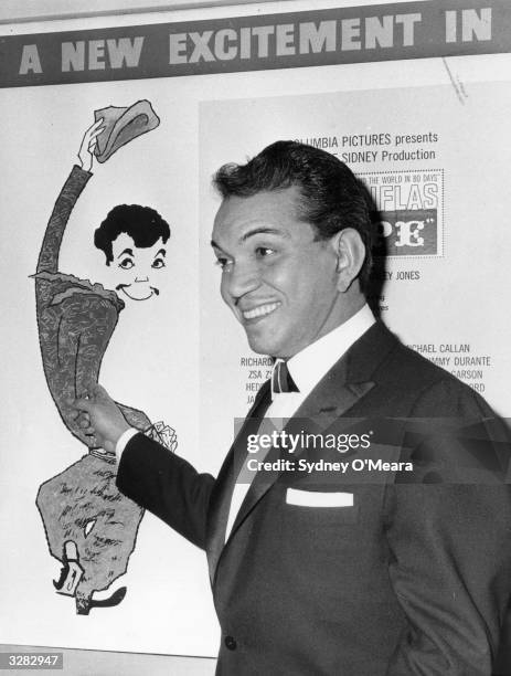 Cantinflas points proudly to a poster of himself at the Columbia film theatre on Shaftestbury Avenue, London, W1.