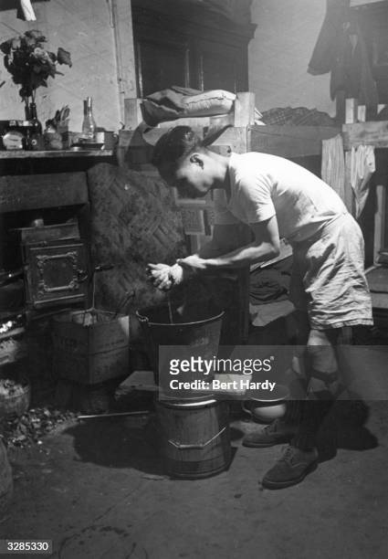 Young man washing himself in a bucket in a Liverpool Chinese hostel. Original Publication: Picture Post - 1136 - Chinese Hostel, Liverpool - unpub.