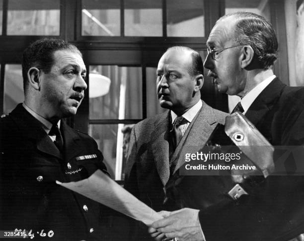 Sidney James plays a policeman opposite Cecil Parker and George Ralph in a scene from the film 'I Believe In You', directed by Basil Dearden and...