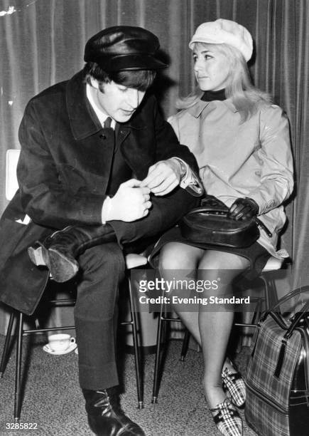 Singer and songwriter John Lennon , of British pop group The Beatles, and his wife Cynthia wait for a flight to New York at London Airport. John is...