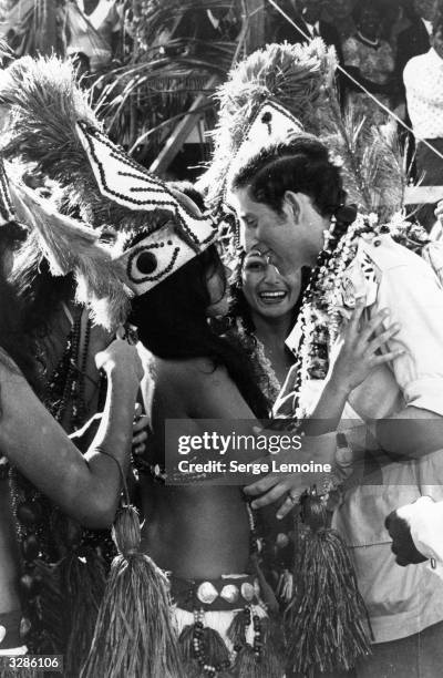 Charles, Prince of Wales holding an admiring dancer's embrace during a Royal tour of Fiji.