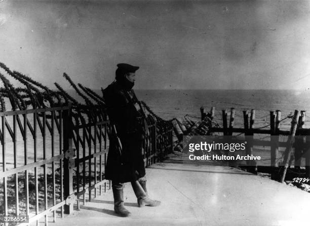 An armed German soldier stands watch on the fortified sea-wall at Helgoland .