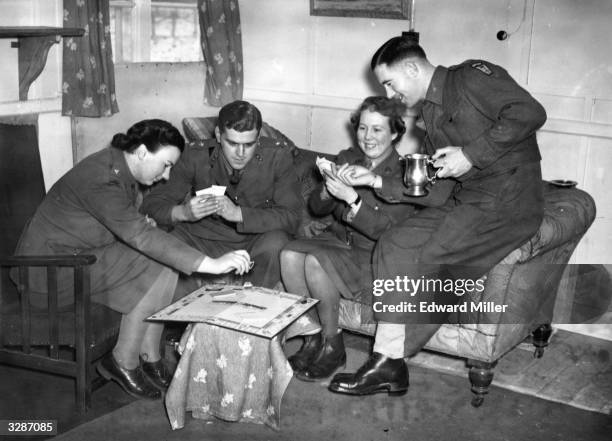 British Army and Auxiliary Territorial Services officers enjoy a game of Monopoly in the shared Officer's Mess.