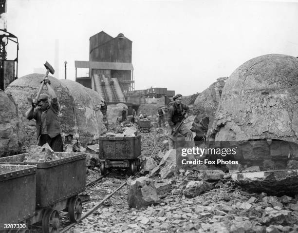 Workers break up the slag from the ladles of the steel works. The end product is used for making roads.