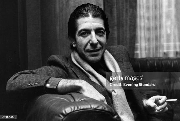 Solemn Canadian folk pop singer-songwriter Leonard Cohen shares a joke and smokes a cigarette.