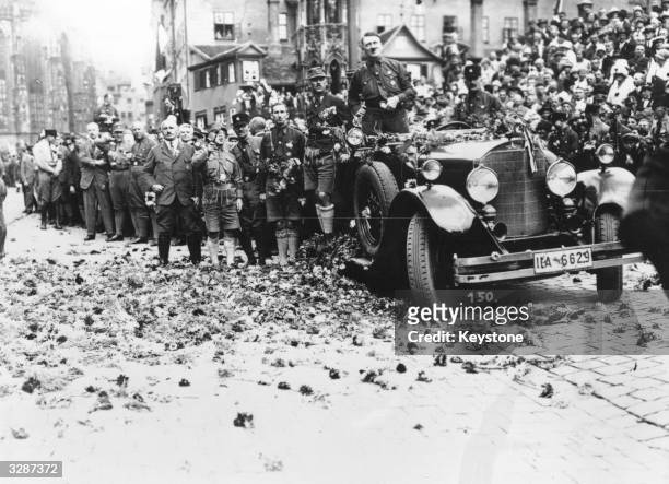 Adolf Hitler drives along a flower strewn road after a rally at Nuremberg.
