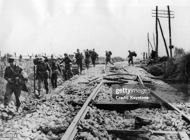 British Infantrymen moving alongside a railway destroyed by the Germans in Italy.