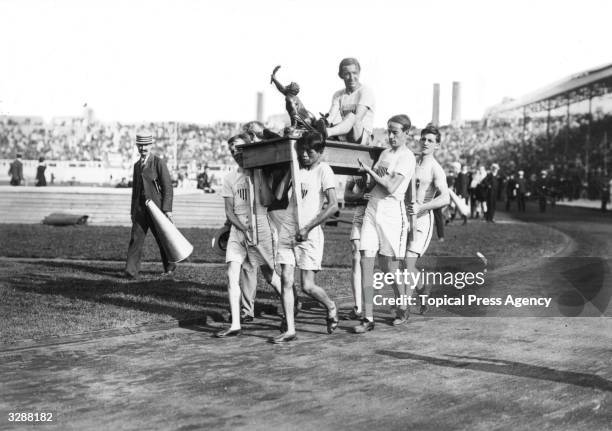 John Hayes of the United States is carried on a table by his team mates on a lap of honour around the White City Stadium after winning the Marathon...