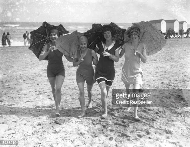 Four bathing belles shading themselves with parasols on the beach at Skegness.