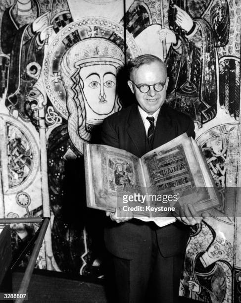 Dr Herbert Parke, chief librarian of Trinity College Dublin, holds the 8th century illuminated manuscript the 'Book of Kells', open at an image of...