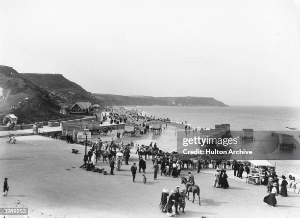 Day-trippers on the North Beach at Scarborough, circa 1913 where they are offered rides, bathing machines and a souvenir stall, as well as the beach...