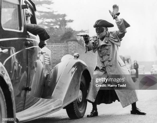 Man collecting money for Hounslow Hospital, dressed up as highwayman Dick Turpin, holds up a motorist in Hounslow to demand a contribution.