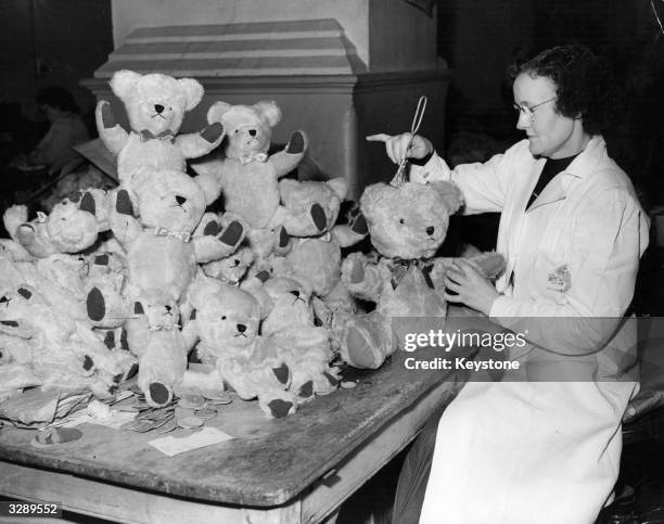 Joyce Rudland, an employee at the Dartford Factory, of the Homeworkers Products Society, Ltd, brushing up the mohair on a completed teddy bear. She...