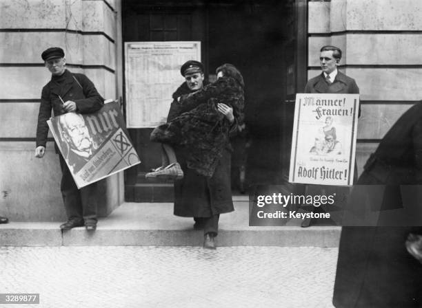 An invalid is carried away from a Berlin polling station by a chauffeur after voting in the second presidential election, which was won by Paul von...