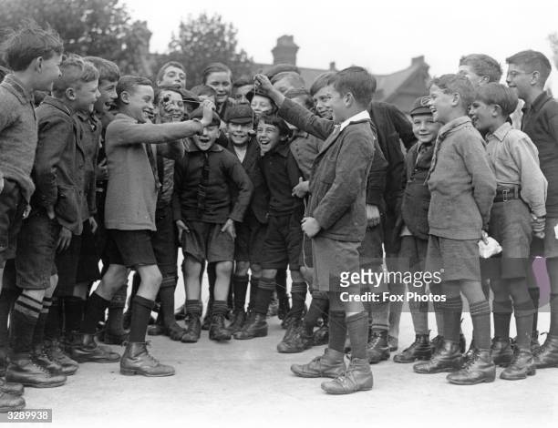 Boys in their uniform shorts and long socks conker fighting in the conker season in Hornsey, London, 1926.