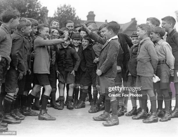 Boys in their uniform shorts and long socks conker fighting in the conker season in Hornsey, London, 1926.