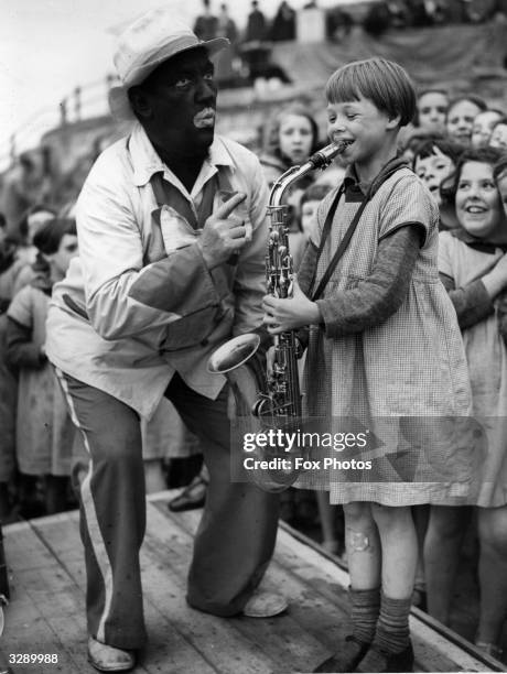 Uncle Bill, a 'blackface' minstrel at Morecambe, entertains poor children from Bradford with his saxophone.