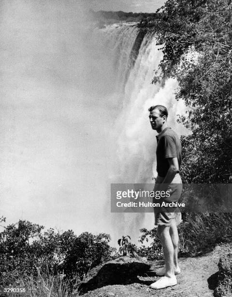 The Duke of Kent , standing on a rock next to a large waterfall.