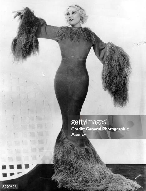 Vaudeville and film actress Mae West modelling an 'hourglass' evening dress.