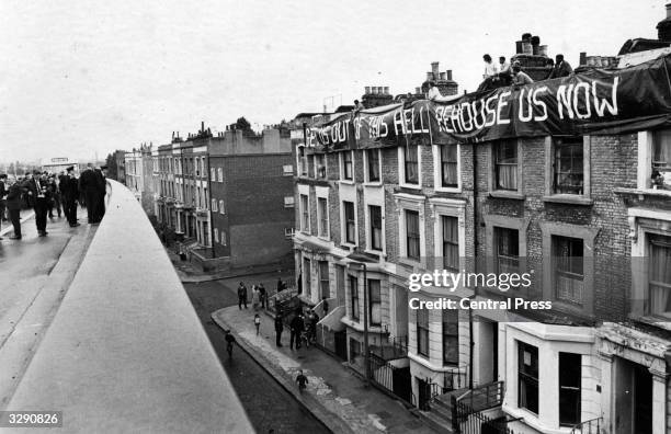 Large banner saying 'Get Us Out Of This Hell Re-house Us Now' flies over a group of homes when the 'Westway' in London was opened.