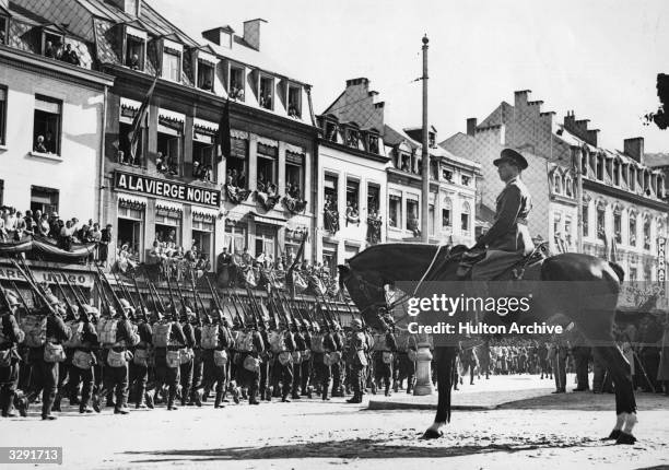 King Leopold III of the Belgians , taking the salute in a march past of the war-ready Belgian army at the time of rising tension in Europe.