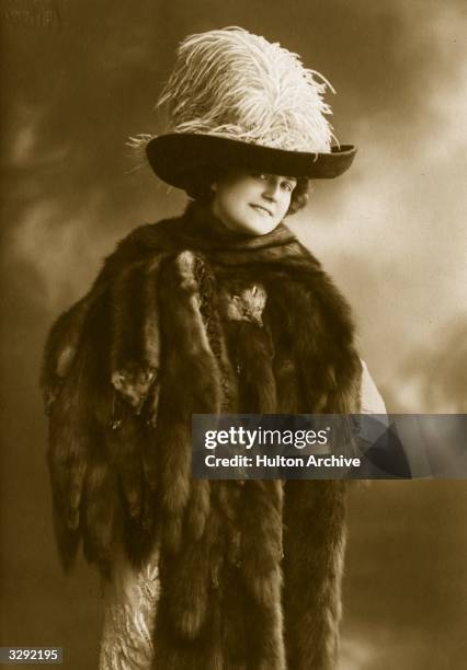 Woman wearing a stole of mink furs, and an ostrich feather hat.