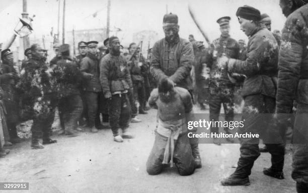 Chinese soldiers stand round as a prisoner is made ready for execution during the 1912 Revolution in China.