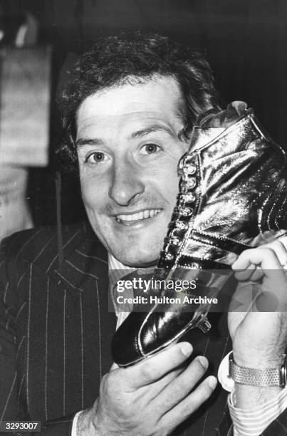 Welsh rugby union player Gareth Edwards holding a real rugby boot dipped in gold. He was given the award by Adidas and the Rugby World magazine for...