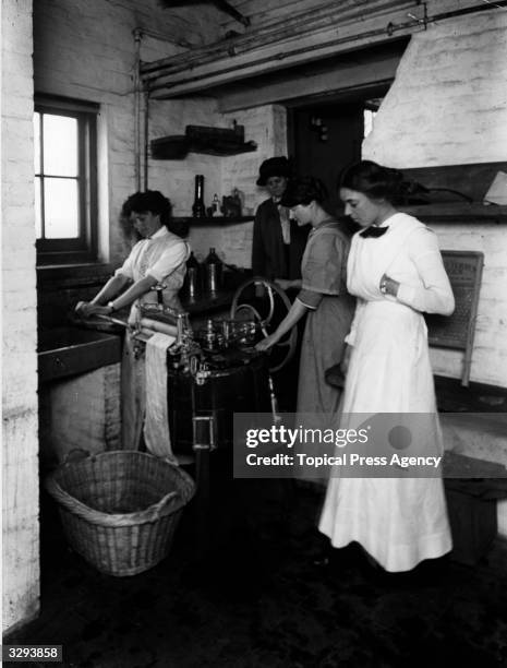 Lady Gwendolen Guinness watches laundry students using a mangle at the Rupert Guinness Training Farm for Women, Hoebridge Farm, Woking. The school is...