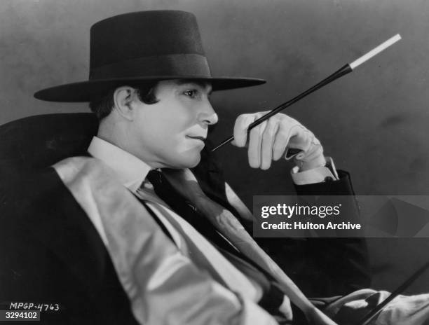 American silent star Harrison Ford poses languidly with a cigarette holder in a scene from the silent comedy 'Proud Flesh', directed by King Vidor...