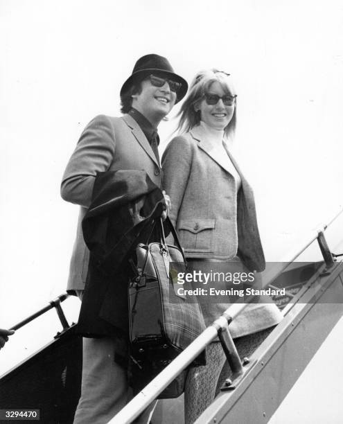 Beatle John Lennon and his wife Cynthia boarding an aeroplane at London Airport.