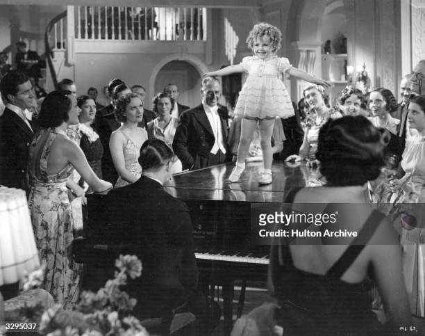 Binkie Stuart , a Shirley Temple doppleganger, tap dances on a piano top to an admiring crowd in 'Little Miss Somebody'. The film was directed by...