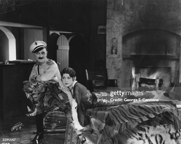 Ben Turpin and Madeline Hurlock who is draped on a large tiger skin in a scene from 'Three Foolish Weeks'. Title: Three Foolish Weeks Studio: Mack...
