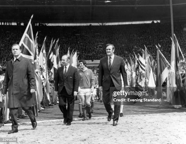 Football team managers Bertie Mee and Don Revie leading their teams, Arsenal and Leeds United, onto the pitch for the FA Cup Final match at Wembley.