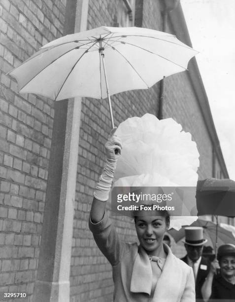 Yvonne Bentley protects her tall hat from the rain on Ladies Day at Ascot racecourse. The hat, which she made herself, is 18 inches high and made of...