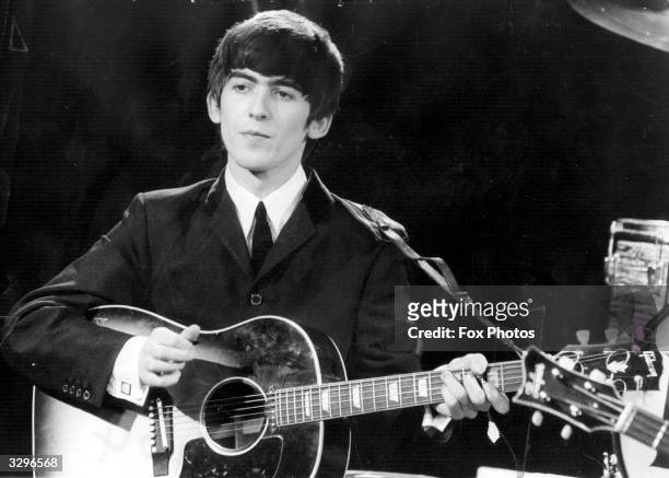 Guitarist and singer George Harrison of the popular Merseybeat group The Beatles, performing during a live concert.