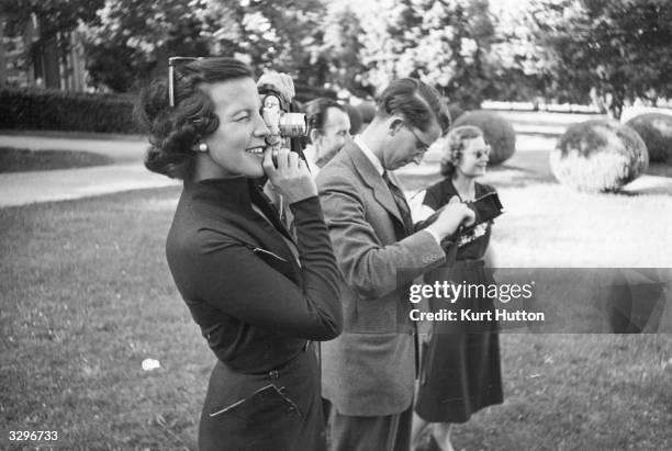 Princess Marie Lilian de Rethy, wife of King Leopold III of Belgium, takes a photograph in the garden of their villa in Pregny, Geneva, where they...